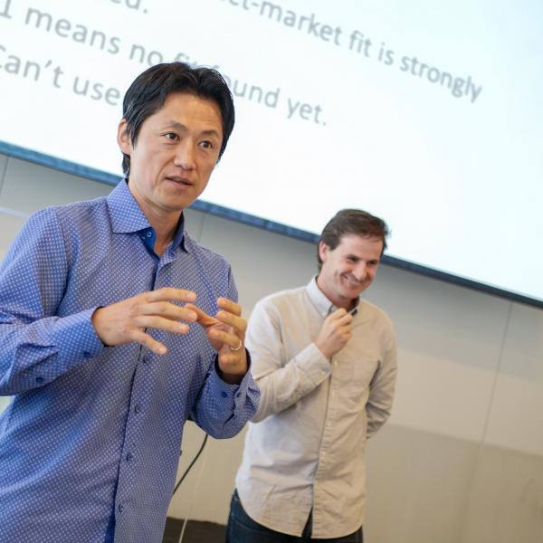 A man wearing a blue shirt, using his hands to explain something 